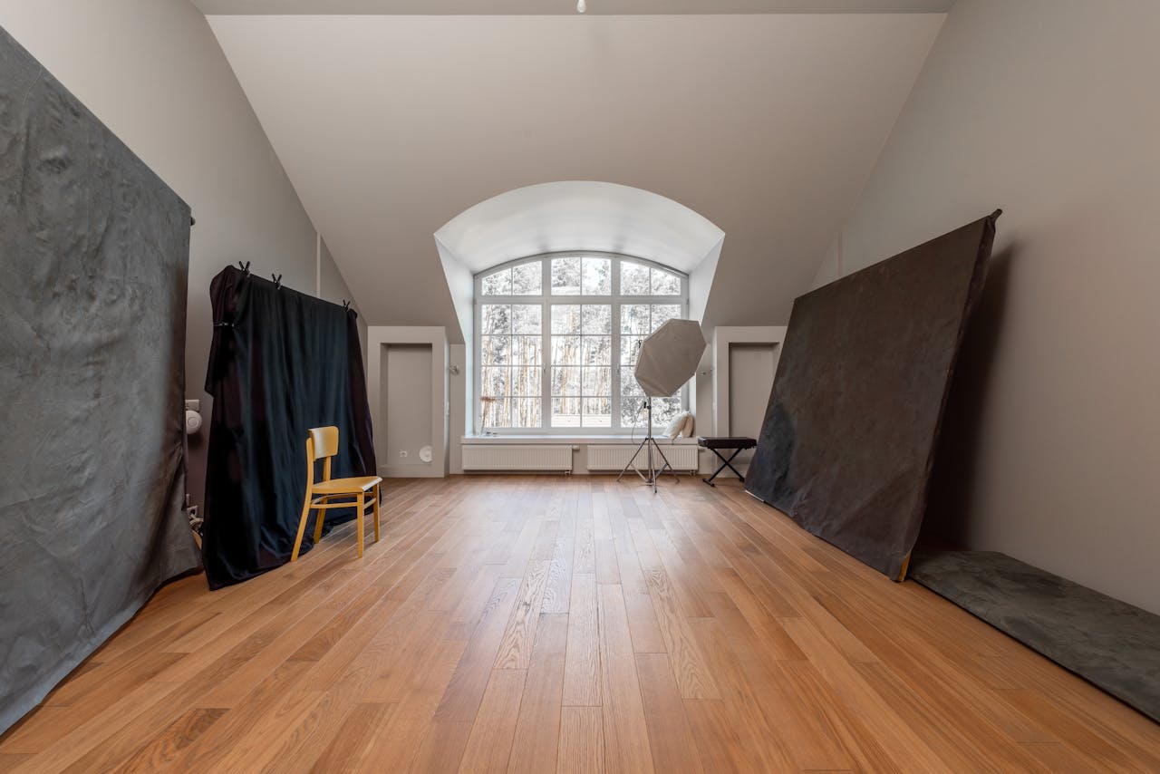 Spacious photography studio with angled ceilings and wooden floors, ideal for creative shoots.